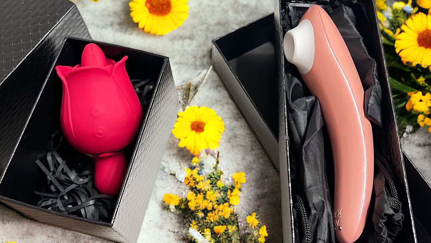 Two boxed adult toys next to flowers, one shaped like a tulip and the other in a sleek design